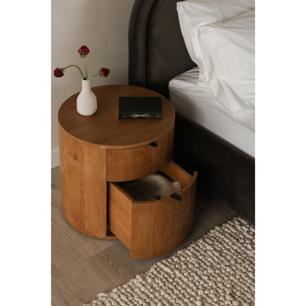 Theo nightstand with an open drawer beside a bed, highlighting its functionality.