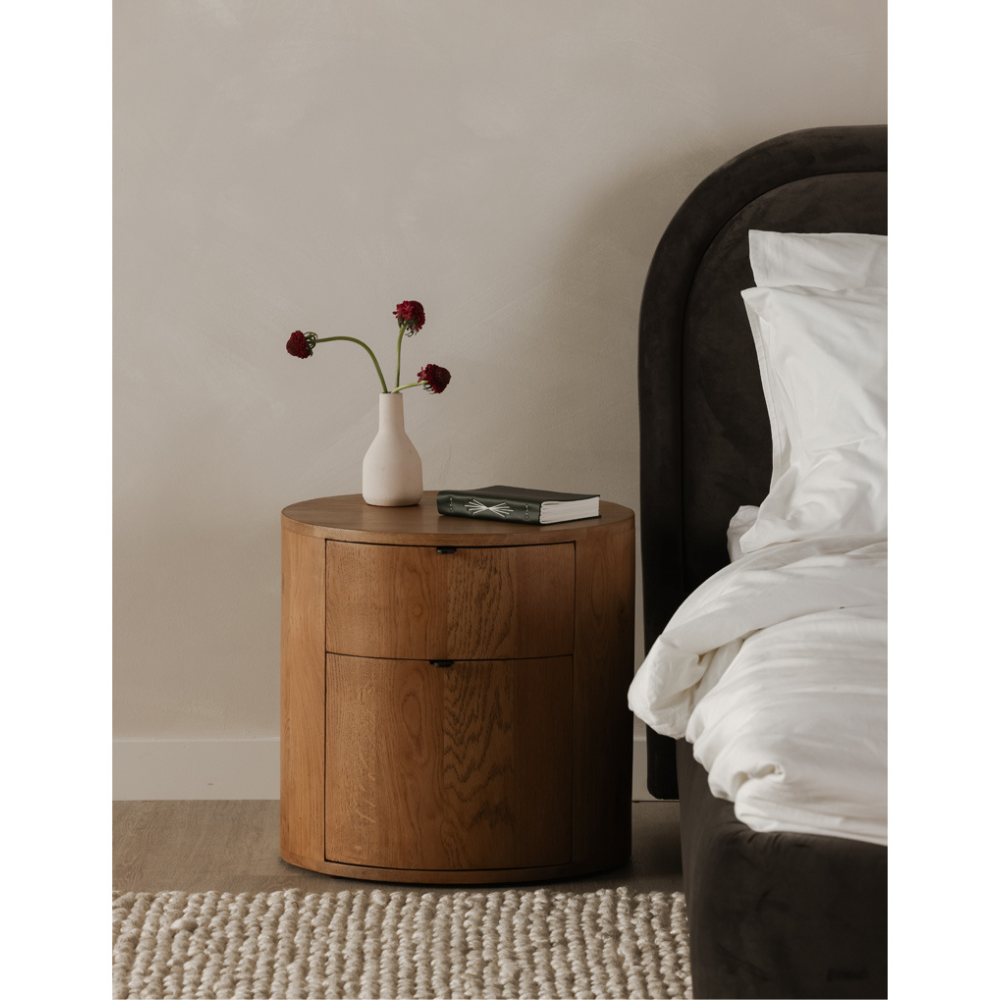 Theo nightstand beside a bed, styled with a vase and book.