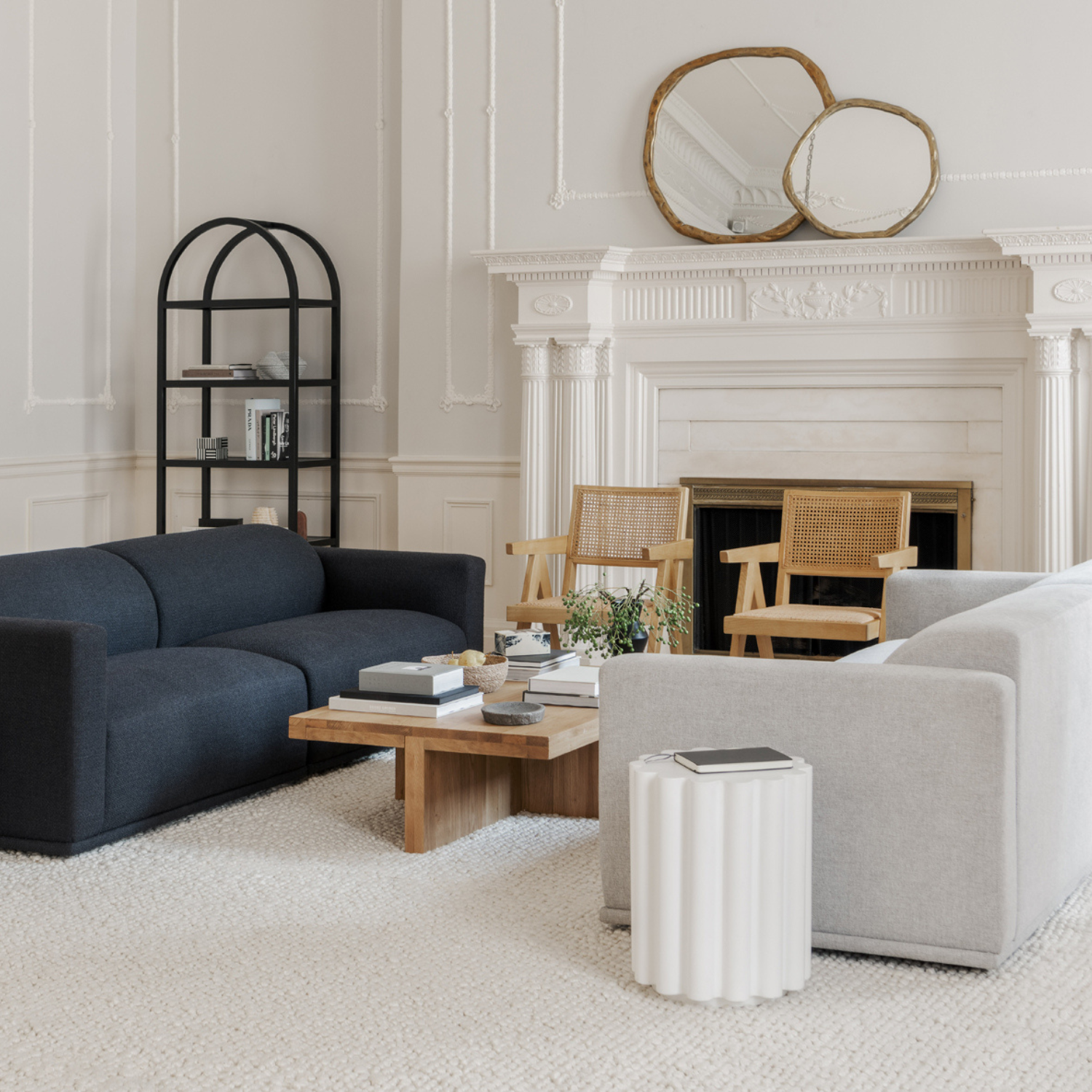 Living room with two natural Takashi chairs by the fireplace, black and gray sofas, and a wooden coffee table.