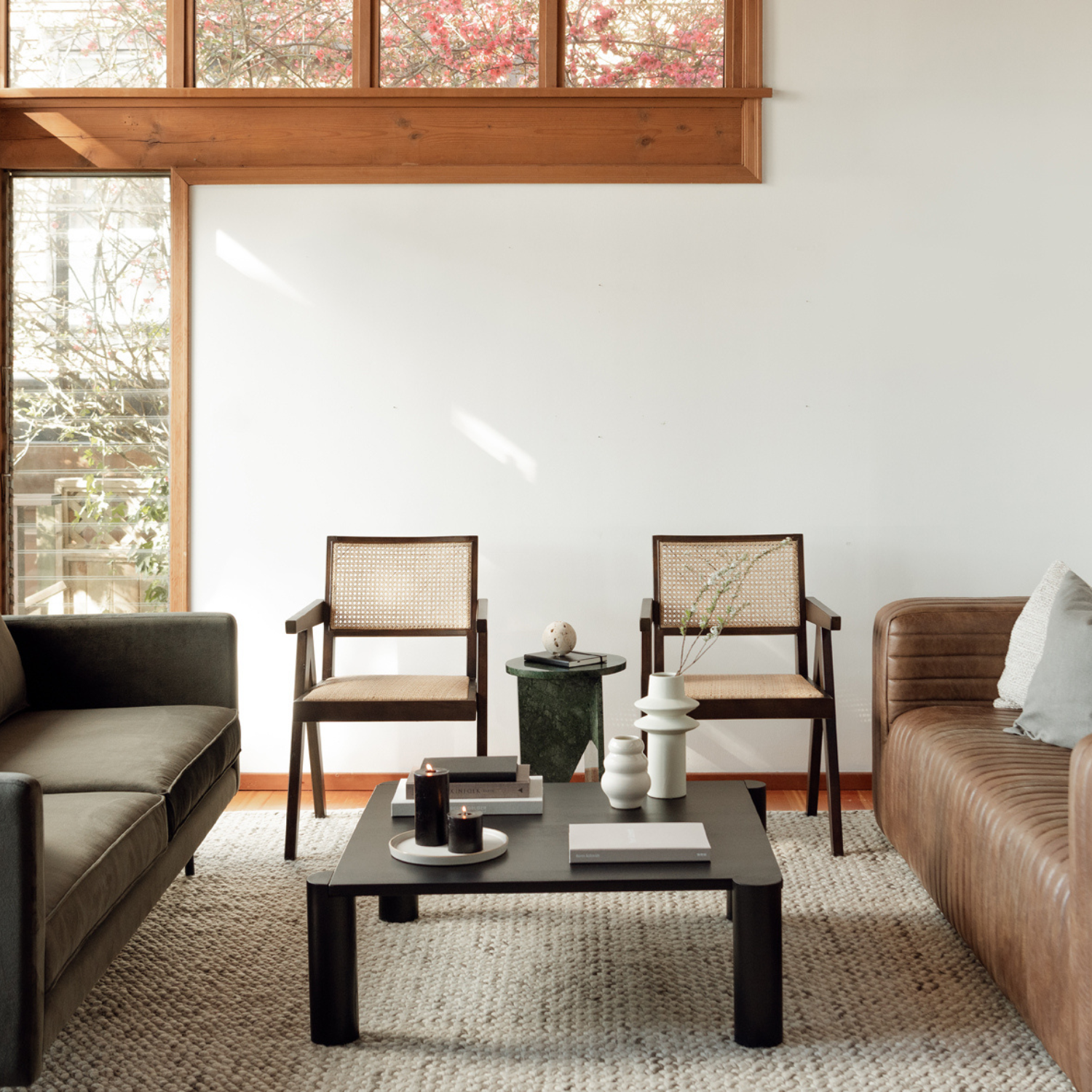 Living room with two Takashi chairs in dark brown, natural rattan, between sofa and leather couch.